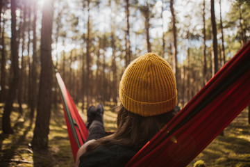 Beautiful young woman relaxing in hammock in forest. Summer scenery, a beautiful morning in the bosom of nature. The girl admires the views and nature. Breathed fresh air. Beautiful morning light.