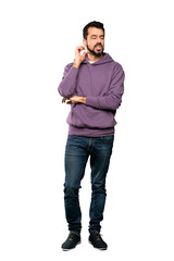 Fototapeta premium Full-length shot of Handsome man with sweatshirt having doubts over isolated white background