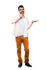 Fototapeta premium Full-length shot of Handsome man with beard holding copyspace imaginary on the palm to insert an ad over isolated white background