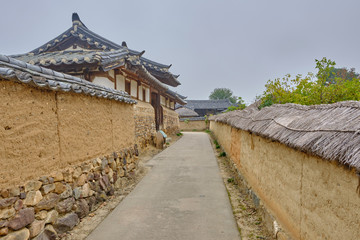 Fototapeta na wymiar Scenic view of old traditional korean house in Hahoe folk village near Andong in South Korea. Beautiful summer cloudy look of building in traditional asian style in small town in Republic of Korea.
