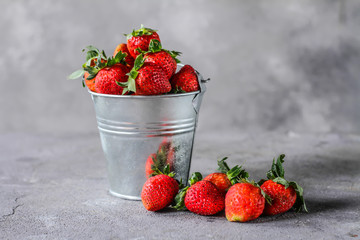 Photo of heap of fresh strawberries in the bowl on rustic grey background..A bunch of ripe strawberries in a can bowl on the table. Copy space. Healthy fresh fruit. Organic food. Clear food
