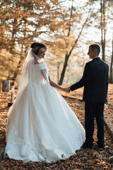 Fototapeta na wymiar Beautiful romantic wedding couple hold each other's hands in park. Married, love, feelings, bridal bouquet. Autumn wedding. Autumn wedding in the park, bride and groom. 