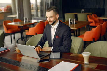 Handsome man in a black suit. Businessman working in a cafe