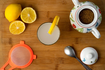 Lemonade with ice, yellow lemons and sugar, on wooden background