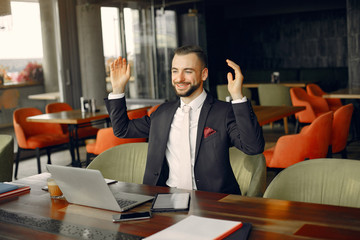 Handsome man in a black suit. Businessman working in a cafe