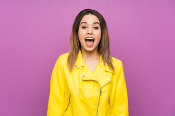 Young woman over purple background with surprise facial expression