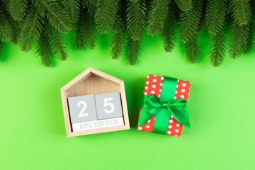 Top view of fir tree, wooden calendar and gift box on colorful background. The twenty fifth of December. Merry Christmas time with empty space for your design
