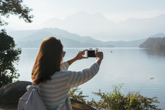 young beautiful girl  take a photo of the view in front on bike trail at the lake in the morning. Active people. Outdoors