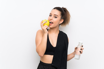 Young sport woman over white wall with an apple