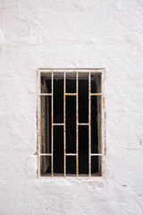 Fototapeta na wymiar Window in a white stone wall, closed by bars.