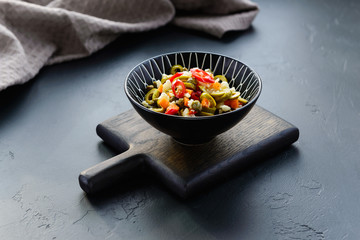 Olive salad for muffuletta in a bowl on a dark wooden board.