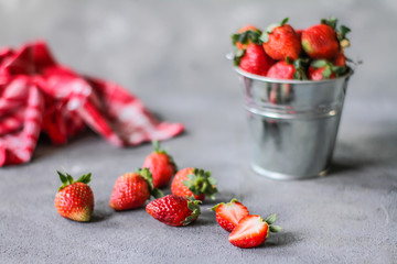 Photo of heap of fresh strawberries in the bowl on rustic grey background..A bunch of ripe strawberries in a can bowl on the table. Copy space. Healthy fresh fruit. Organic food. Clear food