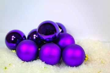 lila Christbaumkugeln im Schnee