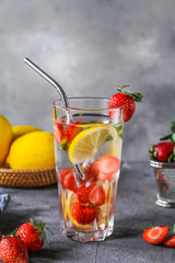 Photo of refreshing summer iced cold drink with strawberry lemon lemonade in glass. Mineral water with fresh strawberries lemon with a grey background. Detox water with strawberry lemon. Copy space.