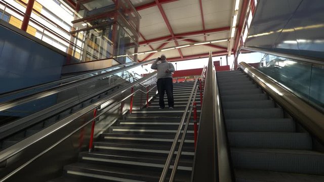 Obese Black Man With White Cap Speaks On The Phone On The Subway Stairs