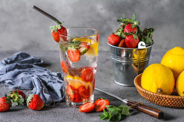 Photo of refreshing summer Strawberry infused waters. Mineral water with fresh strawberries lemon mint with a grey background. Detox water with strawberry lemon mint. Copy space. Wooden box