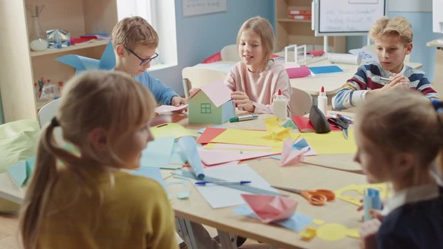 Elementary School Arts & Crafts Class: Diverse Group of Smart Children Have Fun on a Handicraft Project, Using Colorful Paper, Scissors and Glue to Create Fun Papier Mache