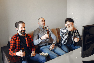 Obraz premium Fans sitting on the couch in the living room. Guys drinking a beer