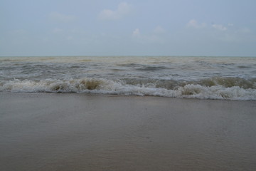 Brown-ish sea waves beside seashore, sand captured in daytime.