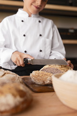Crop baker cutting fresh bread