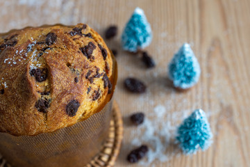 Top view of panettone with Christmas trees, defocused raisins and sugar grains on wooden table in horizontal