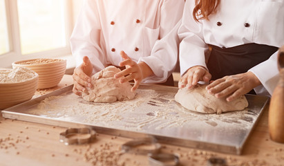 Crop bakers kneading fresh dough