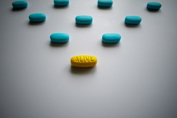 Alive one yellow tablet on the top with many blue ones