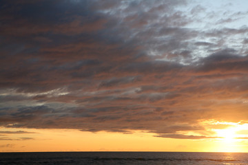 Naklejka na ściany i meble Cloudy sunset at the beach 