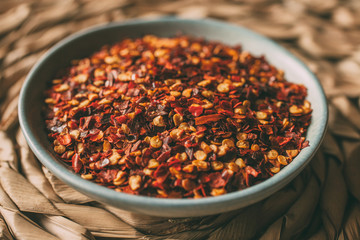 Heap of chili flakes in a bowl. Red cayenne pepper close up.  