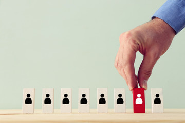 Business concept image of tangram puzzle blocks with people icons over wooden table, human...