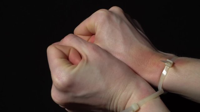 Hands are released from the plastic handcuffs with a missing hostage, a victim of violence and a kidnapped woman. Tied with a handcuffs in emotional stress and pain, calling for help. 4k footage.