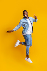 Fototapeta na wymiar Portrait of funny black man jumping on yellow background