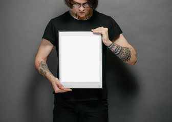 Man holding a picture frame or poster for mock up wearing black clothes