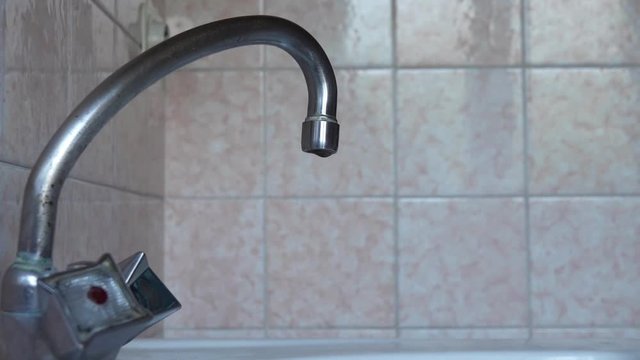 Faucet with dripping water in the kitchen. Leaking water due to installation defect or wear of plumbing. The need for rational use of natural resources.
