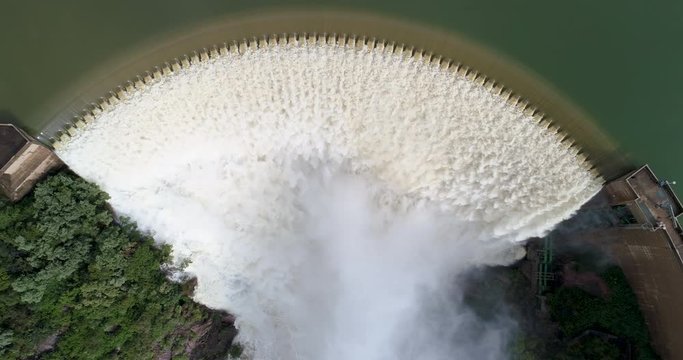 4K aerial zoom out view of water gushing over the concrete arch of the Roodeplaat Dam situated on the Pienaars River, South Africa