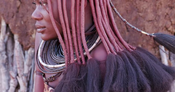 4K close-up tilt up view of a pretty Himba girl showing head gear and neck jewellery,Namibia