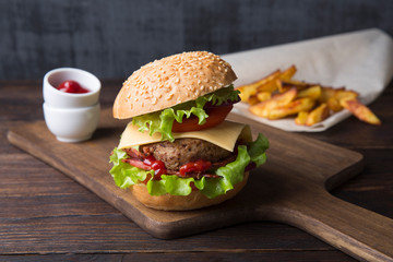 Homemade burger with grilled potatoes, served with ketchup sauce. Burger with beef cutlet.