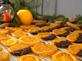 Christmas sweets, candied fruits in chocolate. Caramelized orange slices on a light paper background. Homemade dessert. Cooking sweets. close-up