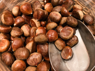 Fresh chestnuts in wooden basket with silver scoop at a farmer market