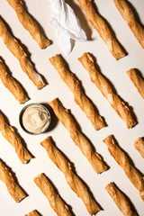 Salted twisted crackers in a line with hummus sauce. Abstract food conception.