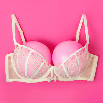 Bra with pink balloons on a pink background. Fun, conceptual photo, great big breasts. Complementary colors.