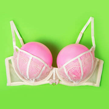 Bra with pink balloons on a green background. Fun, conceptual photo, great big breasts. Complementary colors.