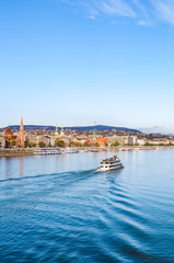 Obraz premium Vertical photo of the Danube river in Budapest, Hungary. Boat on the water. Historical buildings on along the river. Hungarian capital city cityscape. Eastern Europe