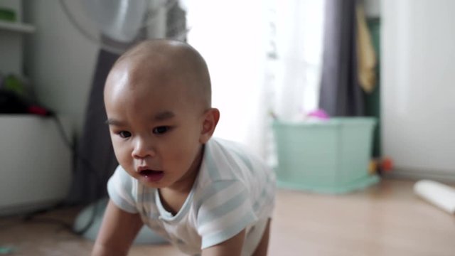 A baby turns around and crawls after the camera. The camera moves backwards.