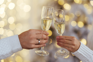 Close up photo of two people holding glasses of shampagne on xmas