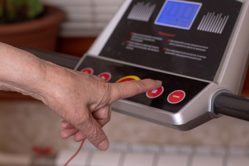 Hands of an old 85 year old woman. Close-up. A woman is engaged at home on a treadmill. Active old age.