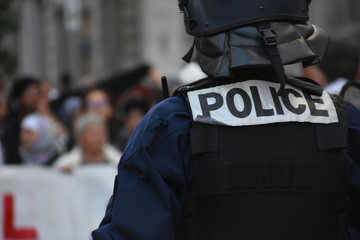 Helmeted policeman force photographed from back during a demonstration