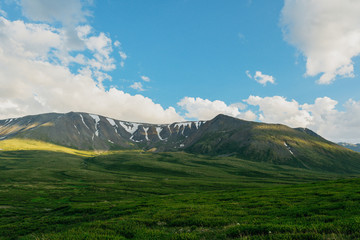 Fototapeta premium Green hills under blue cloudy sky. Mountain valley for pasture