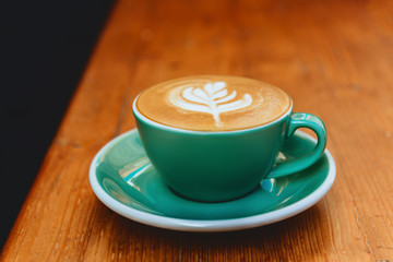cup of cappuccino with latte art on wooden background.