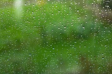 Rain drops on a window against a green background